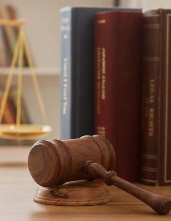 Law books and a judge’s gavel striking a wooden sound block, symbolizing authority, justice, and due process in court proceedings
